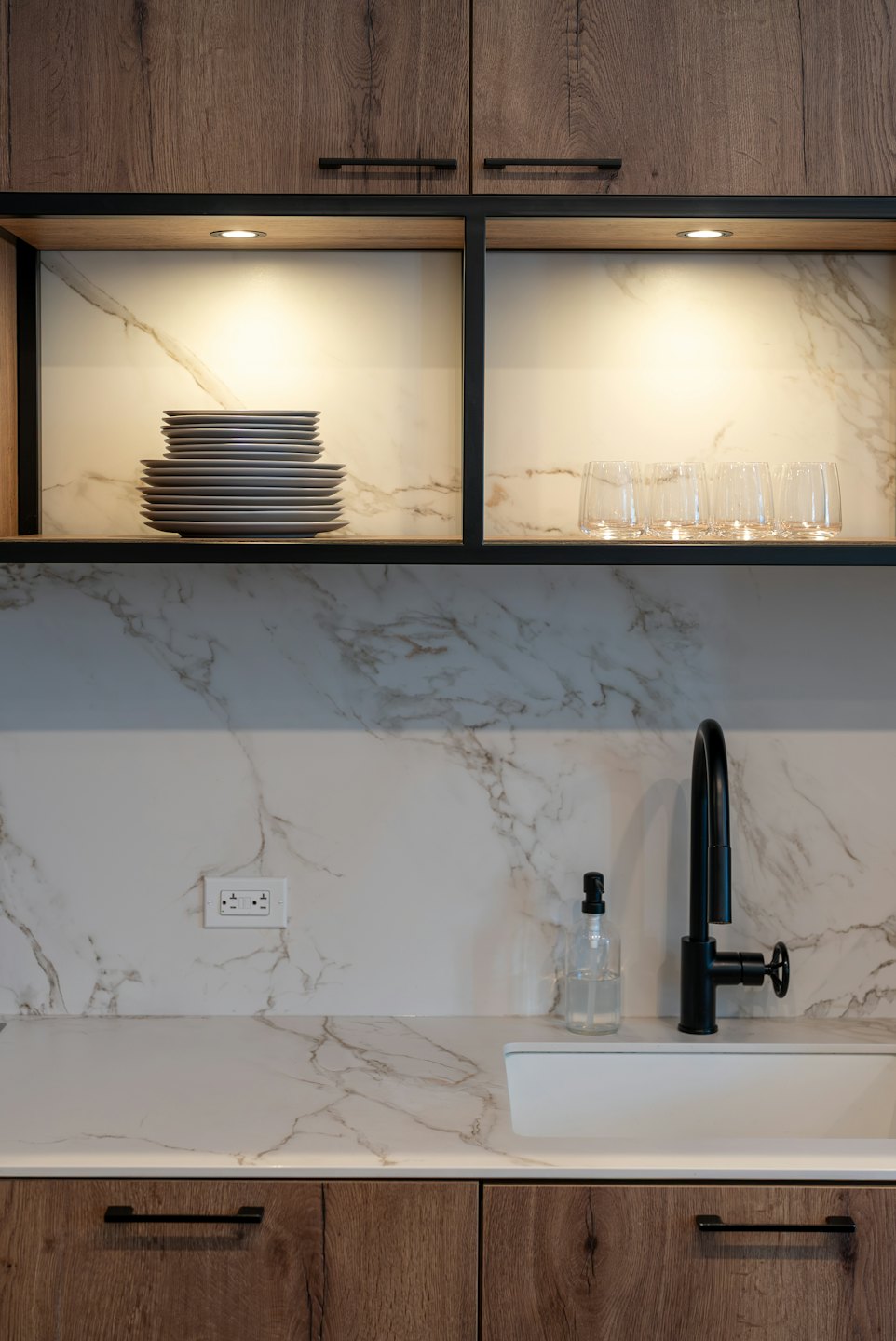 Cucina moderna con piano di lavoro effetto marmo bianco e mobili in legno scuro.