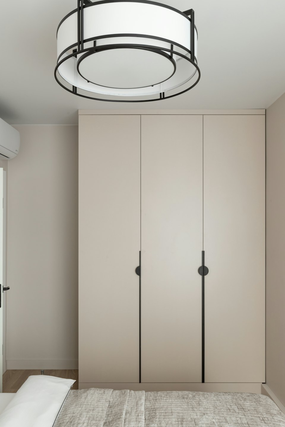 Camera da letto moderna con armadio a muro e lampada circolare a soffitto.
