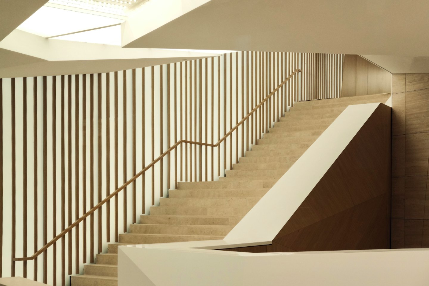 Moderna scala in pietra con doghe di legno sale verso destra.